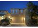 Two-story home with a two car garage, desert landscaping and exterior lighting at dusk at 8558 Rumsfield Ct, Las Vegas, NV 89131