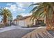 Landscaped front yard featuring gravel, large palm trees and driveway leading to an attached two-car garage at 8805 Pavia Dr, Las Vegas, NV 89117