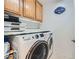 Modern laundry room featuring wooden cabinets, stacked white washer dryer, and shelving at 9071 Ravenhurst St, Las Vegas, NV 89123