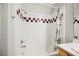 A well-lit bathroom showcases a white tiled tub-shower combination with decorative tile accents at 9725 La Cienega St, Las Vegas, NV 89183