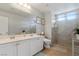 Bathroom featuring double sinks, large mirror, walk-in shower with glass door, and neutral decor at 9792 Valmeyer Ave, Las Vegas, NV 89148