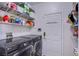 Modern laundry room with a front load washer and dryer, storage shelves, and a white door at 11773 Golden Moments Ave, Las Vegas, NV 89138