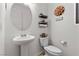 Cozy powder room featuring a pedestal sink, decorative wall art, and a toilet with storage shelves above at 10052 Silver Comet Ct, Las Vegas, NV 89178