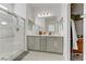 Bright bathroom featuring a dual sink vanity, a glass shower, and neutral tile flooring at 1103 Tektite Ave, Henderson, NV 89011