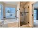 Bright bathroom featuring a soaking tub, a glass-enclosed shower, and a view to the outside at 1110 Legato Dr, Las Vegas, NV 89123