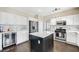 Modern kitchen features stainless appliances, white cabinets, dark island, and tiled backsplash at 1426 Clipperton Ave, Henderson, NV 89074