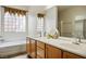 Bathroom featuring double sink vanity, soaking tub, and glass block window at 2629 Chateau Clermont St, Henderson, NV 89044