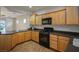 Well-lit kitchen featuring wooden cabinetry, black appliances, and tile flooring at 2629 Chateau Clermont St, Henderson, NV 89044