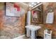 Stylish half bathroom featuring a pedestal sink, decorative mirror and textured wall art at 2967 Pinehurst Dr, Las Vegas, NV 89109