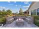 Beautiful stone fire pit with built-in seating, surrounded by lush landscaping and brick pavers at 3018 Fall Solstice Ct, Las Vegas, NV 89138