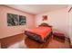 An interior bedroom area featuring hard wood floors, a window, and a bed with orange comforter at 4409 Cinderella Ln, Las Vegas, NV 89102