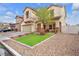 Attractive home showcasing a tidy yard, lush synthetic grass, rock ground cover, and stone-accented entry, offering modern appeal at 4822 Jade Ridge St, North Las Vegas, NV 89081