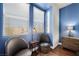 Bright bedroom featuring blue accent wall, wood floors, and a reading nook with two leather chairs at 511 Via Ripagrande Ave, Henderson, NV 89011