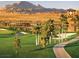 A view of a community with homes, a golf course, palm trees, and a clock tower against mountains at 511 Via Ripagrande Ave, Henderson, NV 89011