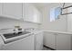 Well-lit laundry room with white cabinets, modern washer and dryer and beautiful patterned tile flooring at 511 Via Ripagrande Ave, Henderson, NV 89011