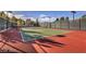 A fenced tennis court with red and green surfaces, ready for a friendly match in a private community at 511 Via Ripagrande Ave, Henderson, NV 89011