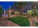 Lush backyard featuring manicured lawn, mature trees, and stone pergola for outdoor enjoyment at 6 Fire Rock Ct, Las Vegas, NV 89141