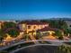 Elegant two-story home with red tile roof, stone accents, and meticulously landscaped front yard at dusk at 6 Fire Rock Ct, Las Vegas, NV 89141