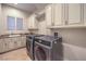 Spacious laundry room with white cabinets, granite counters, tile floor, and modern washer and dryer at 6 Fire Rock Ct, Las Vegas, NV 89141