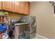 Efficient laundry room with front loading washer and dryer and overhead cabinets at 6944 Puetollano Dr, North Las Vegas, NV 89084