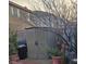 Storage shed, backyard bench, and potted plants with mature trees in background at 7186 Cressida Ct, Las Vegas, NV 89113