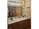 Bathroom featuring double sinks, warm-colored wood cabinets, and a large mirror at 7186 Cressida Ct, Las Vegas, NV 89113