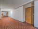 View of the carpeted hallway leading to unit, with a wooden door to the right at 725 N Royal Crest Cir # 213, Las Vegas, NV 89169