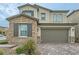 Two-story home showcasing a stone exterior, brown shutters, a two car garage and landscaped yard at 8125 Skye Vineyard Dr, Las Vegas, NV 89166