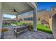 A covered back patio features pavers, ceiling fan, and comfortable outdoor furniture overlooking a well-manicured backyard at 9007 Antora Summit St, Las Vegas, NV 89166