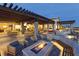 Outdoor patio with a stone fire pit, cushioned chairs, a stone bench, and overhead pergola for dining and relaxation at 9007 Antora Summit St, Las Vegas, NV 89166