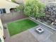 An aerial shot of a backyard with green turf, a stone fire pit, and a retaining wall at 945 Pomander Point Pl, Henderson, NV 89012