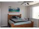 Bedroom with a view from the window, wooden bed frame, coastal art, ceiling fan and plantation shutters at 945 Pomander Point Pl, Henderson, NV 89012