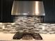 Close-up of stainless steel hood, tile backsplash, granite countertops, and the cooktop in the gourmet kitchen at 945 Pomander Point Pl, Henderson, NV 89012