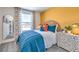 Stylish bedroom with a woven headboard, bright mustard-colored accent wall, and ample natural light at , North Las Vegas, NV 89084