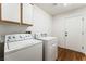 Bright laundry room with white appliances, cabinets, and a modern door leading to other parts of the home at 10029 Netherton Dr, Las Vegas, NV 89134