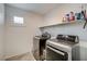 Modern laundry room features stainless steel washer and dryer, a shelf, and a window for natural light at 10699 Sariah Skye Ave, Las Vegas, NV 89166