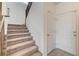 Carpeted staircase featuring a wooden handrail and a door to a lower level or garage at 10699 Sariah Skye Ave, Las Vegas, NV 89166