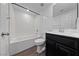 Bathroom featuring a shower-tub combo, white tile surround and a black vanity with white sink at 120 Campbelltown Ave, Henderson, NV 89015