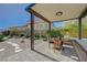 Covered patio area with outdoor seating and views of the backyard with desert landscaping at 12422 Tudor Arch Dr, Las Vegas, NV 89138