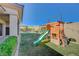 Large backyard with green grass, block fencing, play structure, and a dining area at 12422 Tudor Arch Dr, Las Vegas, NV 89138