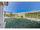 Backyard with green grass, dining area, and a block wall with climbing plants at 12422 Tudor Arch Dr, Las Vegas, NV 89138