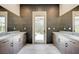 Modern bathroom featuring double vanity sinks, tile floors, and a glass door to the backyard at 12422 Tudor Arch Dr, Las Vegas, NV 89138