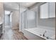 Well-lit bathroom featuring a large soaking tub, glass-enclosed shower, and vanity with wood-look flooring at 183 Baru Belin Ave, Las Vegas, NV 89183