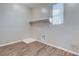 Bright laundry room with wood-look flooring, utility sink hookups, a shelf, and a window at 183 Baru Belin Ave, Las Vegas, NV 89183