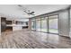 Open-concept living area with wood-look floors, sliding glass doors to the backyard, and a ceiling fan at 183 Baru Belin Ave, Las Vegas, NV 89183