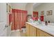 Bright bathroom features a single sink vanity with framed mirror, matching towels, and a decorative red shower curtain at 2537 Nashira St, Henderson, NV 89044