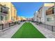 View of community space with green grass, pavers, and wrought iron fencing between beige modern townhomes at 2657 Fawn Beige Ct, North Las Vegas, NV 89086