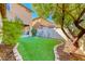 Well-maintained backyard with green artificial turf, enhanced by lush trees and landscaping at 3204 Romanesque Art Ave, Henderson, NV 89044