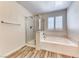 Bright bathroom featuring a separate shower and soaking tub with wood-look flooring at 3204 Romanesque Art Ave, Henderson, NV 89044