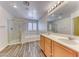 Bright bathroom featuring double sinks, separate shower, and soaking tub with wood-look flooring at 3204 Romanesque Art Ave, Henderson, NV 89044